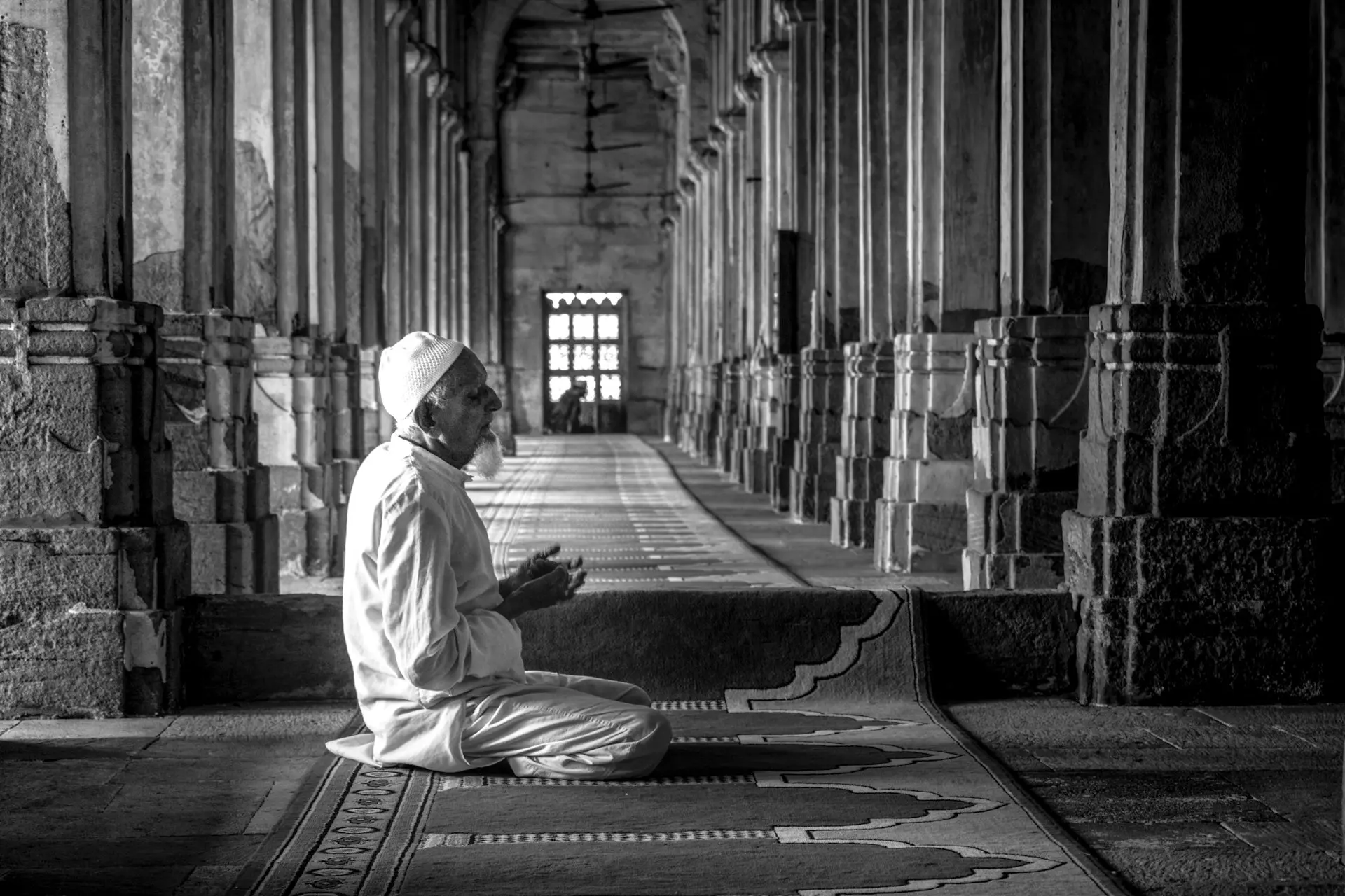 A worshipper seated in prayer inside a historic mosque